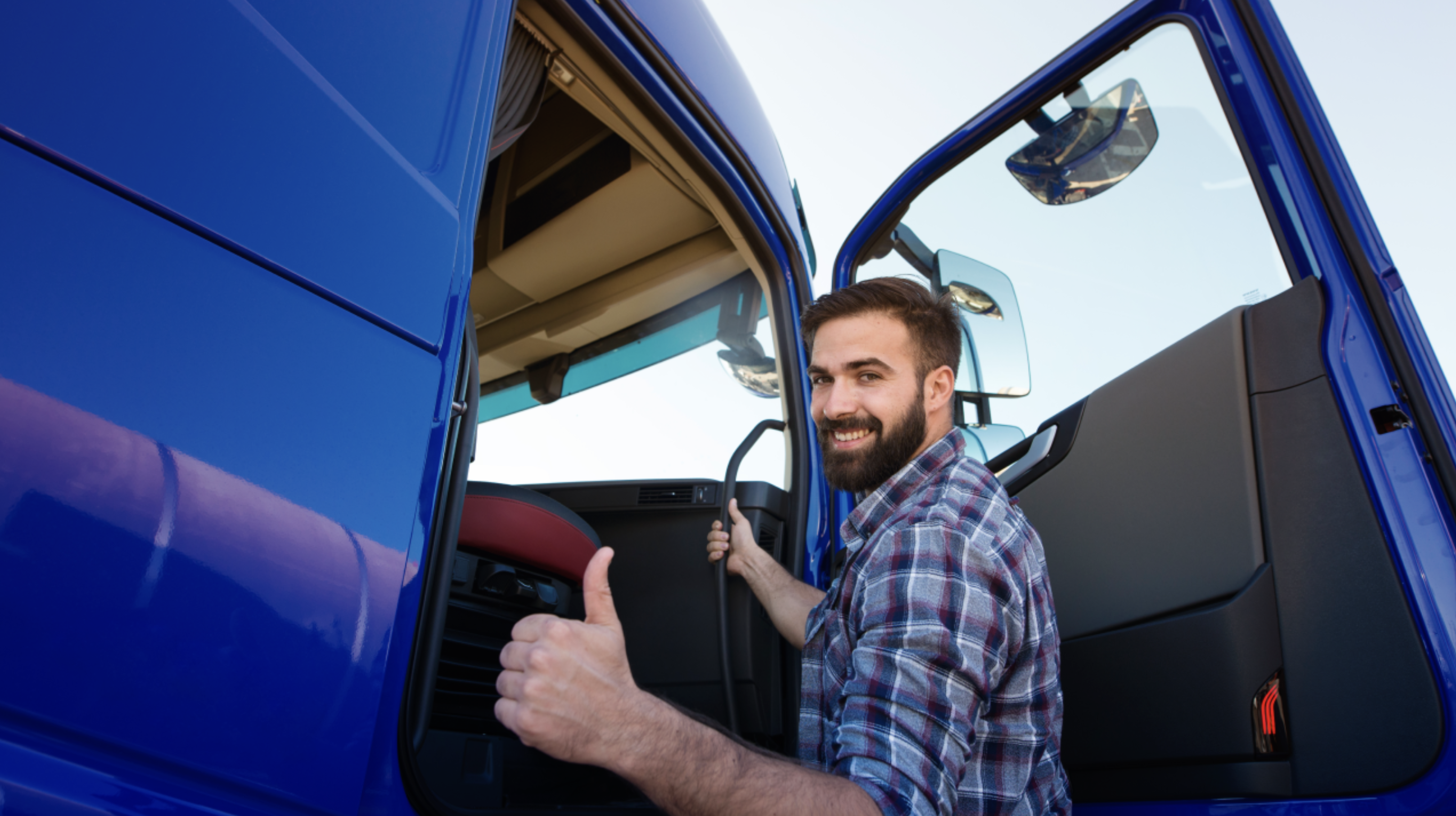 Truck driver in the cab of a blue truck